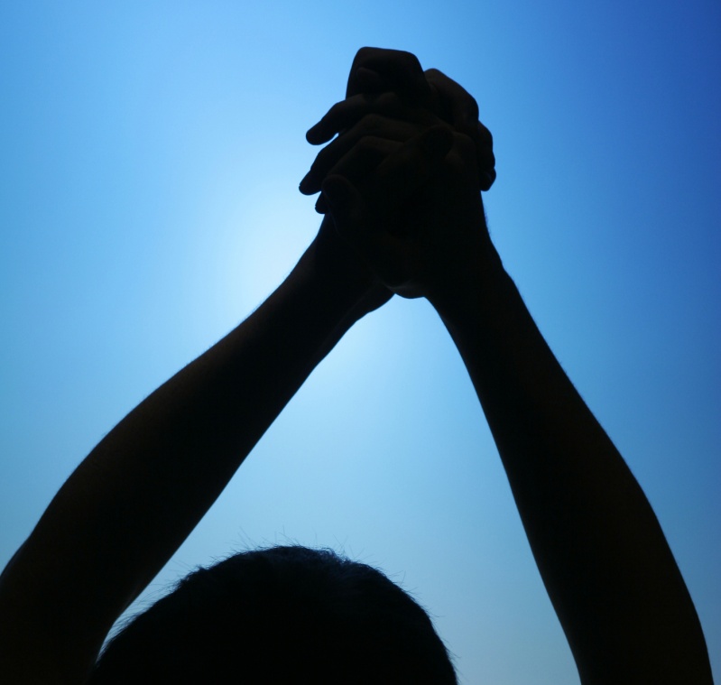 hands raised in victory shadow-blue sky_799x760